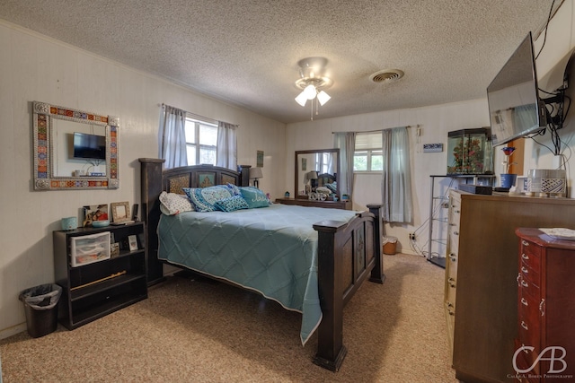 bedroom with a textured ceiling, visible vents, and multiple windows