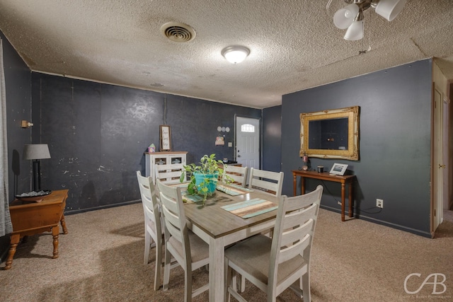 carpeted dining room featuring baseboards, visible vents, a textured ceiling, and ceiling fan