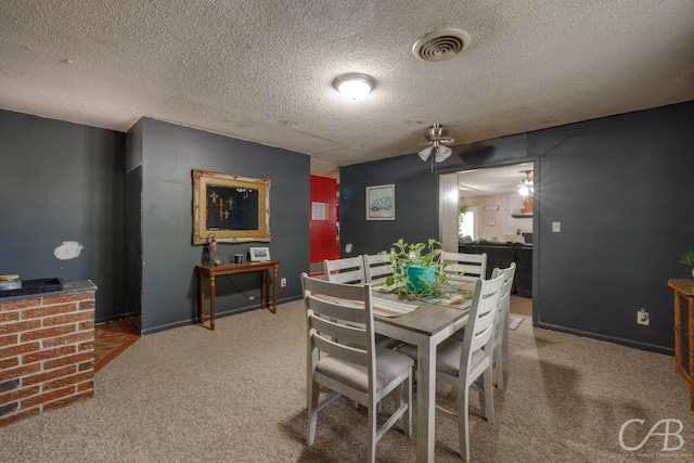 carpeted dining area with visible vents, a textured ceiling, and ceiling fan