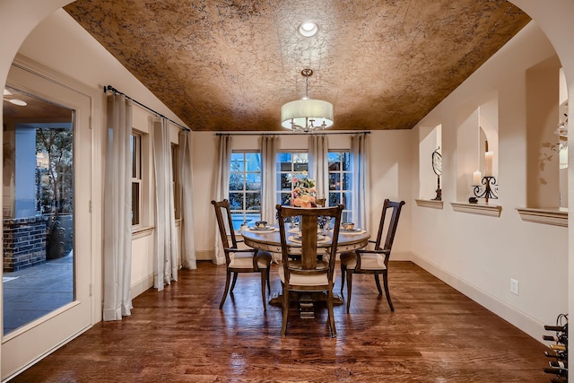 dining room with arched walkways, dark wood finished floors, and baseboards