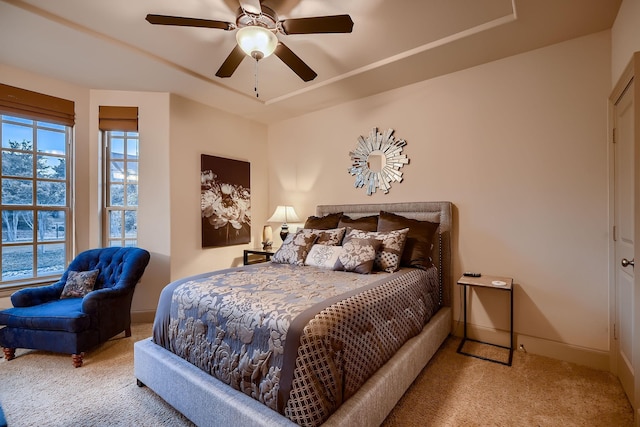 bedroom with a raised ceiling, baseboards, a ceiling fan, and carpet