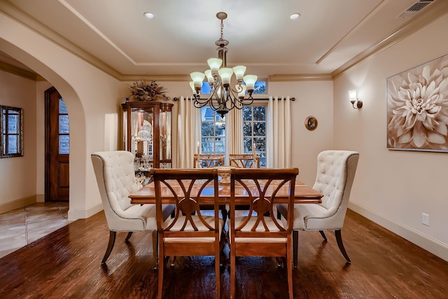dining room with wood finished floors, a chandelier, arched walkways, baseboards, and visible vents