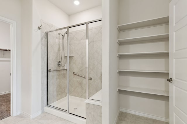 full bathroom featuring baseboards, a shower stall, and a walk in closet