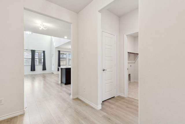 corridor featuring baseboards and light wood-type flooring