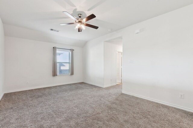 carpeted spare room featuring lofted ceiling, baseboards, visible vents, and ceiling fan