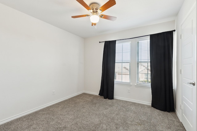 carpeted spare room with a ceiling fan and baseboards