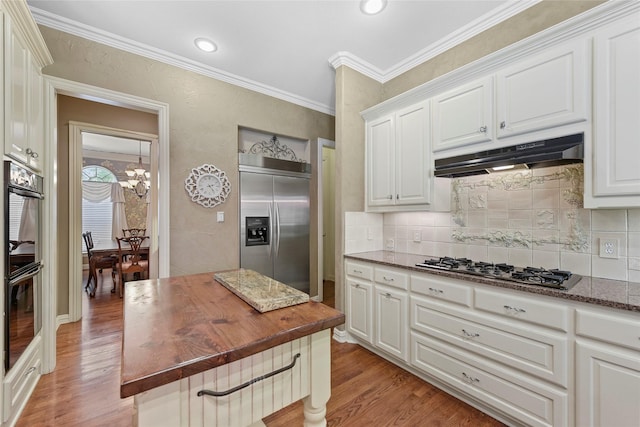803 Eagle Pass, Heath, TX 75032 - kitchen with appliances with stainless steel finishes, under cabinet range hood, wooden counters, light wood-style floors, and decorative backsplash