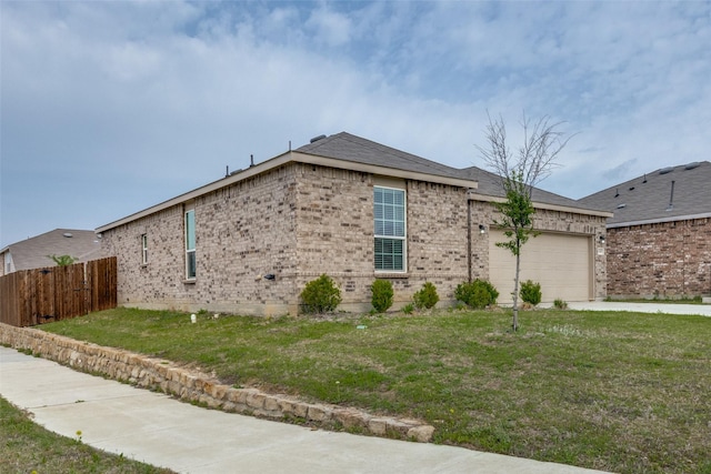view of side of property featuring fence, brick siding, a yard, and a garage