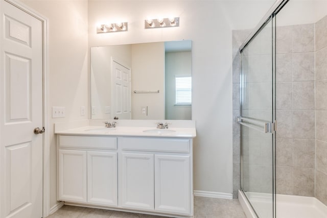 full bathroom with baseboards, a sink, double vanity, and a stall shower