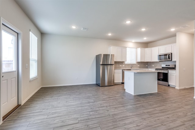 kitchen with visible vents, light wood-style floors, backsplash, and appliances with stainless steel finishes