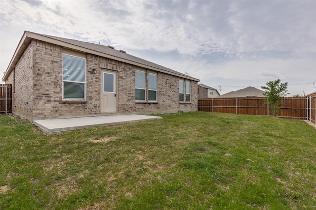 back of house featuring brick siding, a patio area, a lawn, and a fenced backyard