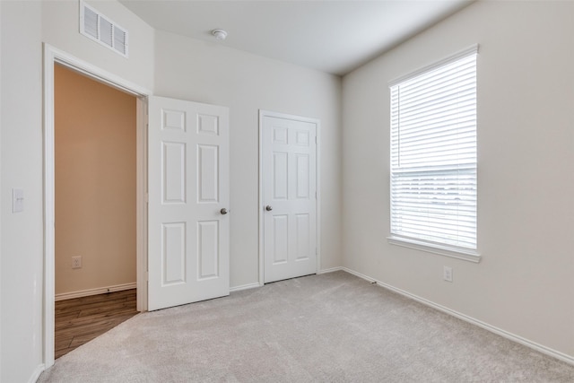 unfurnished bedroom featuring light carpet, visible vents, and baseboards