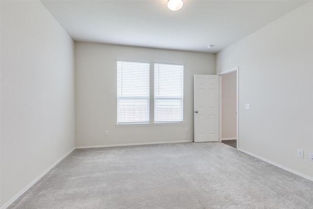 spare room with baseboards, light colored carpet, and a healthy amount of sunlight
