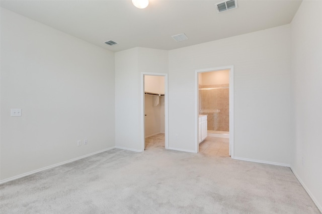 unfurnished bedroom with baseboards, visible vents, a spacious closet, and light colored carpet