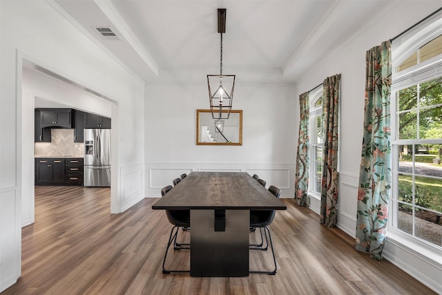 dining room featuring a decorative wall, a wainscoted wall, a tray ceiling, dark wood finished floors, and visible vents