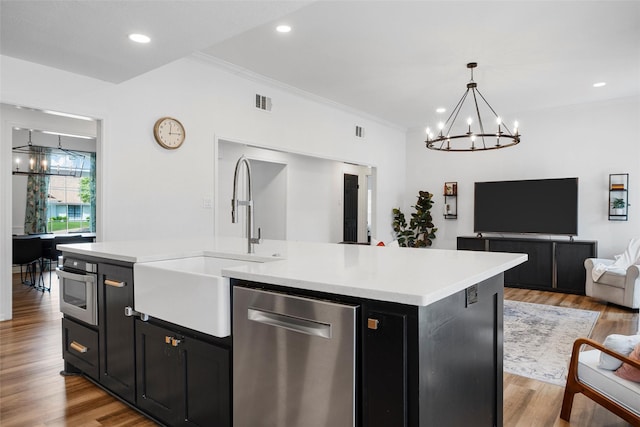 kitchen with dark cabinets, light countertops, an inviting chandelier, appliances with stainless steel finishes, and open floor plan