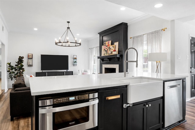 kitchen featuring dark cabinetry, open floor plan, dishwasher, and crown molding