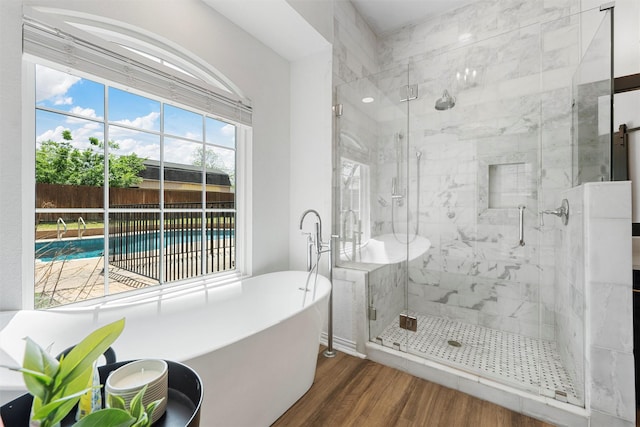 full bath featuring a soaking tub, a stall shower, and wood finished floors
