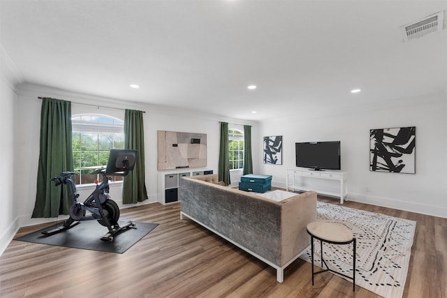 living area with baseboards, visible vents, recessed lighting, wood finished floors, and crown molding