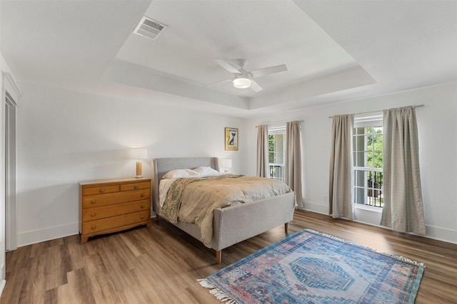 bedroom featuring a tray ceiling, visible vents, and baseboards
