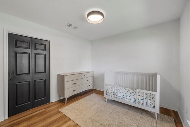 bedroom featuring baseboards, wood finished floors, and visible vents