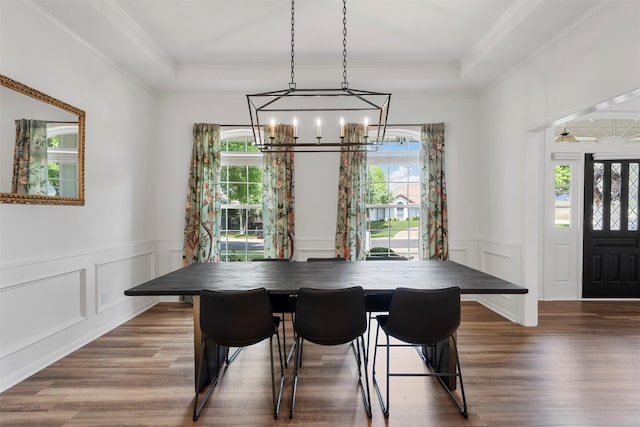 dining space with a decorative wall, wood finished floors, a healthy amount of sunlight, and a notable chandelier