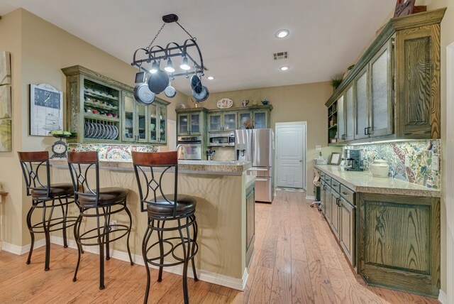 kitchen featuring a peninsula, light wood-style floors, visible vents, and stainless steel appliances