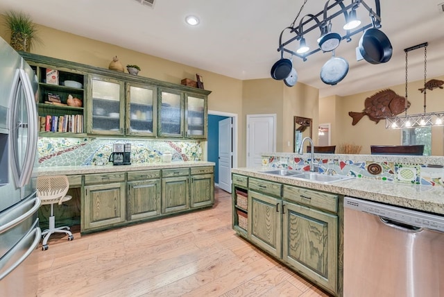 kitchen with green cabinetry, appliances with stainless steel finishes, a sink, and light countertops