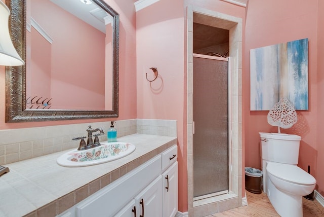 bathroom with toilet, a stall shower, backsplash, wood finished floors, and vanity