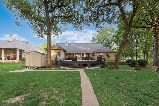 back of property featuring a shed, a chimney, an outdoor structure, a yard, and a wooden deck