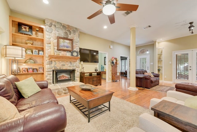 living room featuring a ceiling fan, light wood finished floors, visible vents, and decorative columns