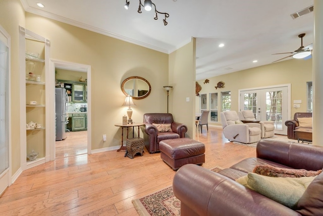 living room featuring crown molding, light wood-style floors, visible vents, and a ceiling fan