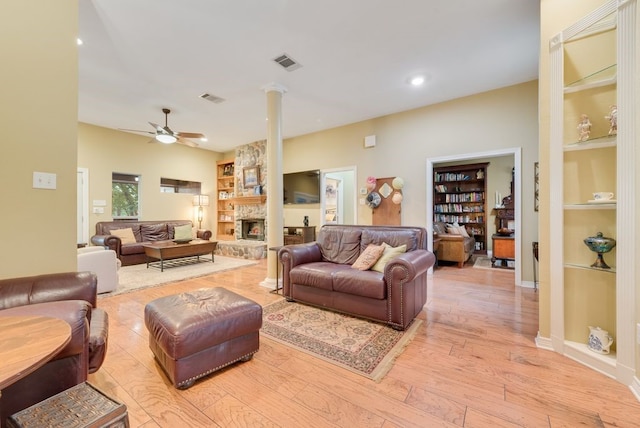 living room with visible vents, light wood-style floors, built in shelves, and ceiling fan