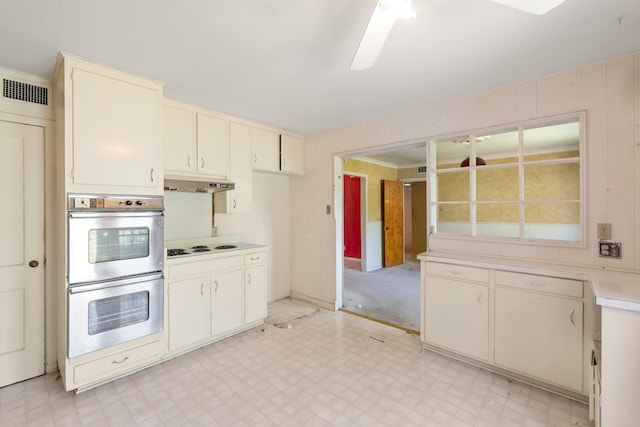 kitchen featuring stainless steel double oven, under cabinet range hood, light floors, light countertops, and visible vents