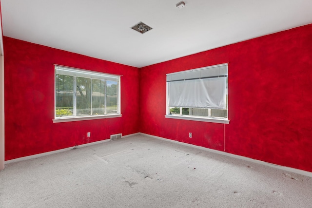 carpeted empty room with plenty of natural light, baseboards, and visible vents