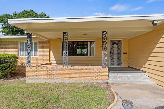 doorway to property with brick siding and a porch