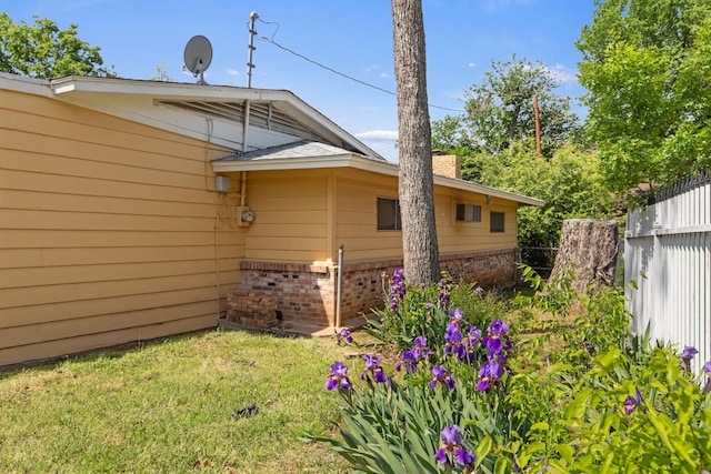exterior space with fence, a lawn, a chimney, and brick siding