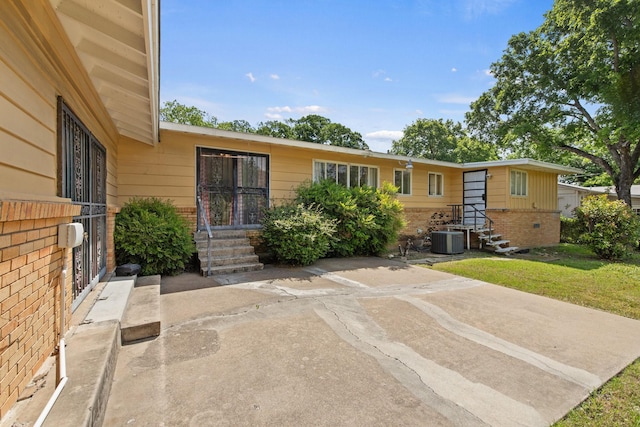 view of front of house with brick siding, cooling unit, and a front yard