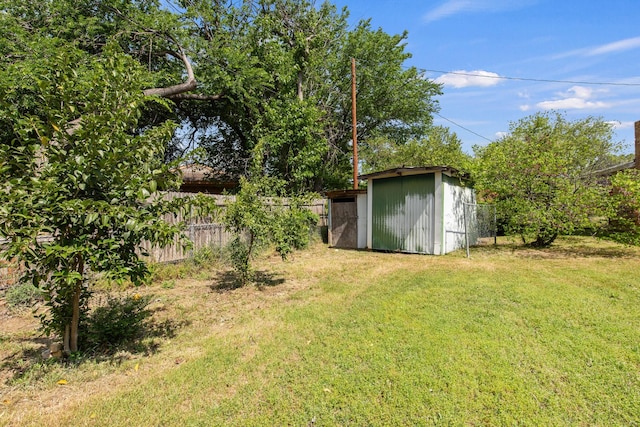 view of yard featuring fence, an outdoor structure, and a storage shed