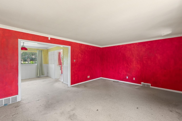 spare room featuring carpet floors, baseboards, ornamental molding, and visible vents