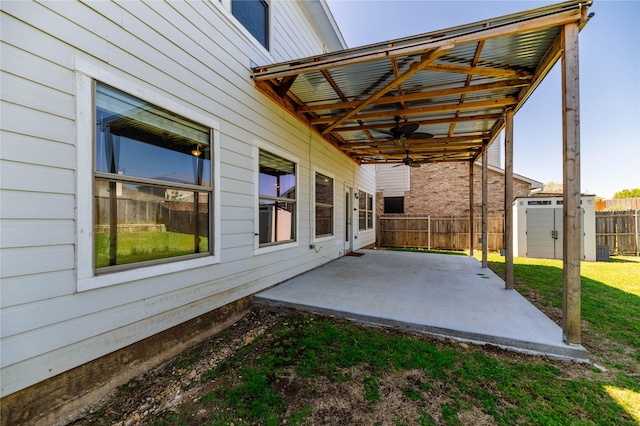 view of patio with a storage unit, fence, an outbuilding, and ceiling fan