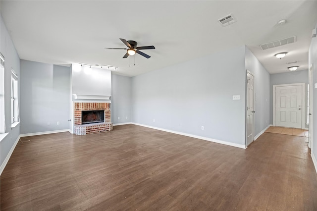 unfurnished living room with dark wood-type flooring, visible vents, and a ceiling fan