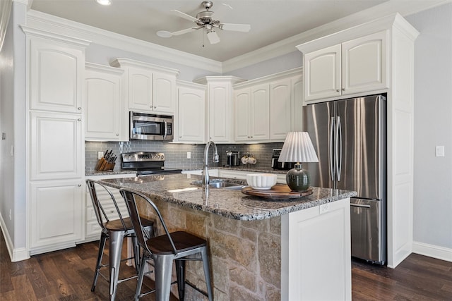 kitchen featuring dark wood-style floors, a sink, baseboards, tasteful backsplash, and appliances with stainless steel finishes