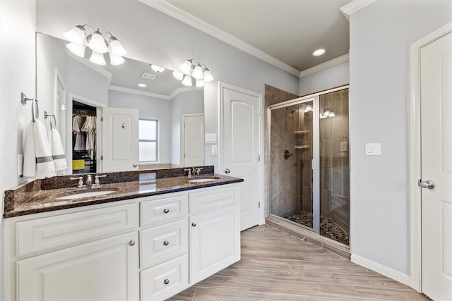 bathroom with double vanity, a shower stall, ornamental molding, and a sink