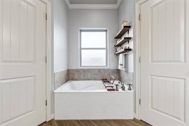 bathroom with a bath, wood finished floors, and ornamental molding