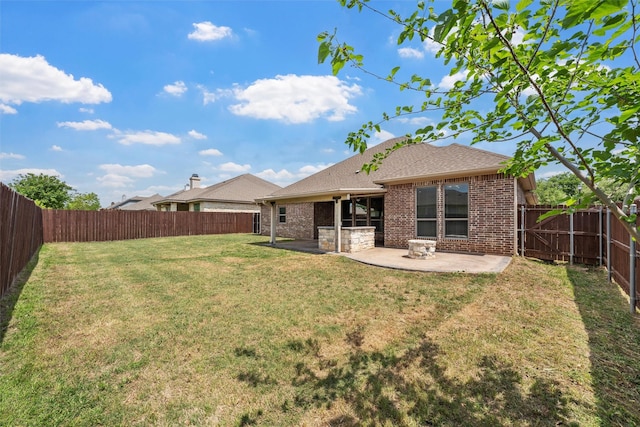 rear view of house featuring a fenced backyard, brick siding, a lawn, a shingled roof, and a patio