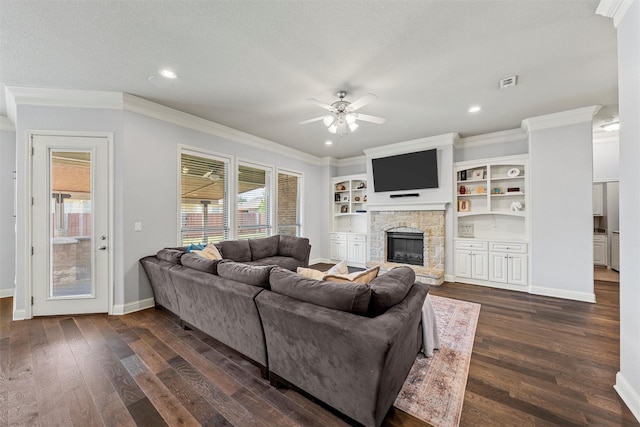 living room featuring dark wood-style flooring, a ceiling fan, a stone fireplace, baseboards, and ornamental molding
