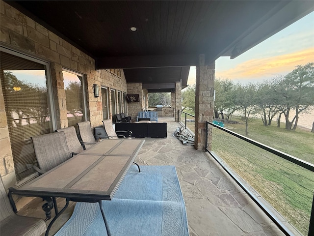 patio terrace at dusk with outdoor lounge area and a balcony