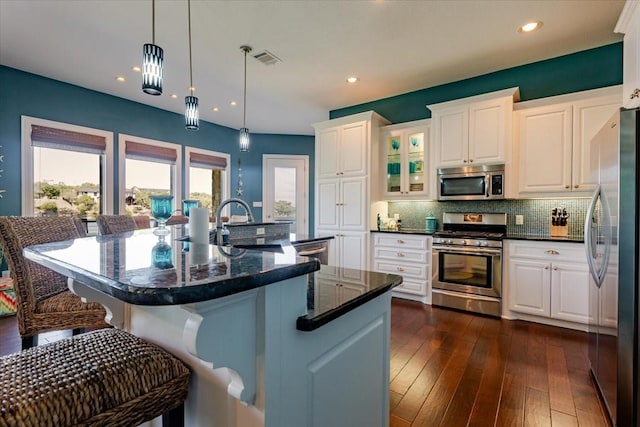kitchen with tasteful backsplash, a sink, white cabinets, appliances with stainless steel finishes, and visible vents