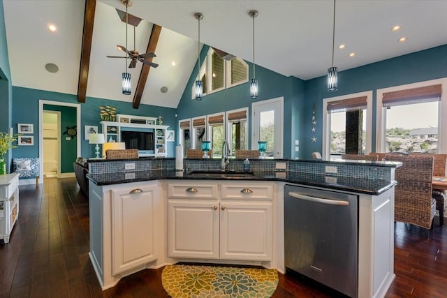 kitchen with dark stone countertops, a sink, open floor plan, dishwasher, and dark wood finished floors